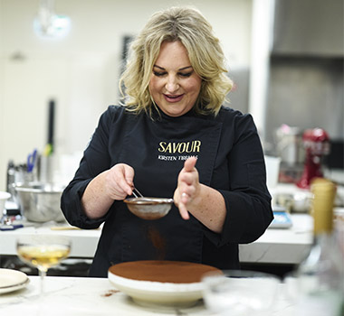 Kirsten Tibballs dusting chocolate over a cake in her patisserie school Savour