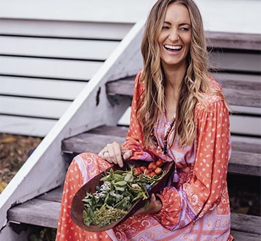 Mindy Woods sitting on stairs holding a bowl of leaves