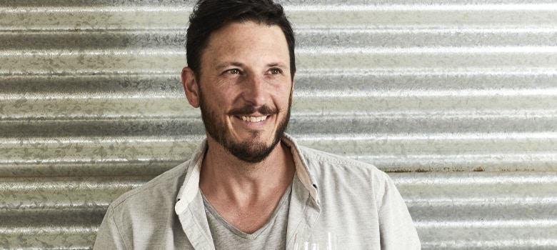 Rowly Milhinch holding a bottle of wine and a wine glass.