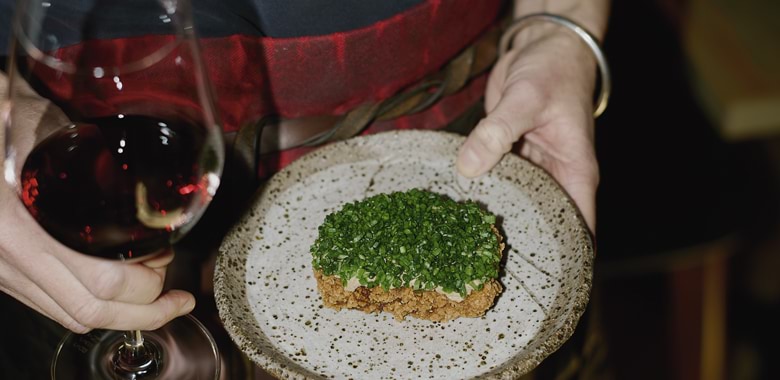 Zoe Birch's crumbed lion's mane mushroom schnitzel and chives next to a glass of red wine