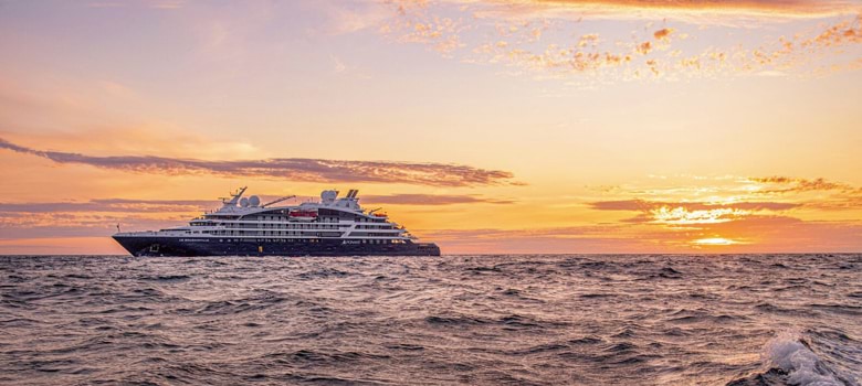 A Ponant Explorations cruise ship on the water at sunset