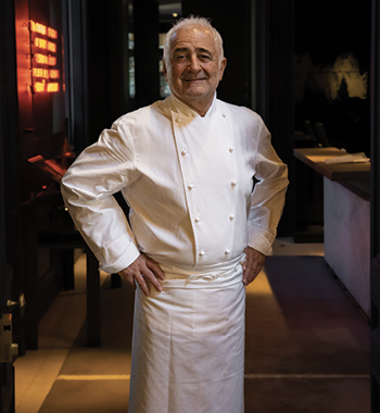 French chef Guy Savoy stands smiling inside his restaurant of the same name