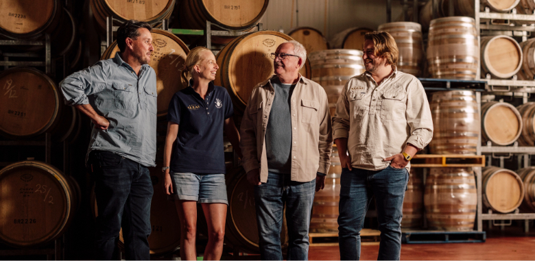 The winemaking team at House of Arras gathered in a room of wine barrels.