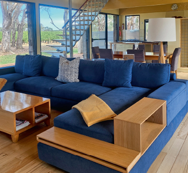 A room at Punter's Retreat Vineyard, showing a blue couch and expansive views of the vines outside.